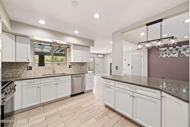 kitchen featuring appliances with stainless steel finishes, backsplash, dark stone counters, sink, and white cabinets