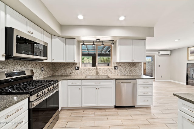 kitchen featuring a wall mounted AC, sink, white cabinets, and stainless steel appliances