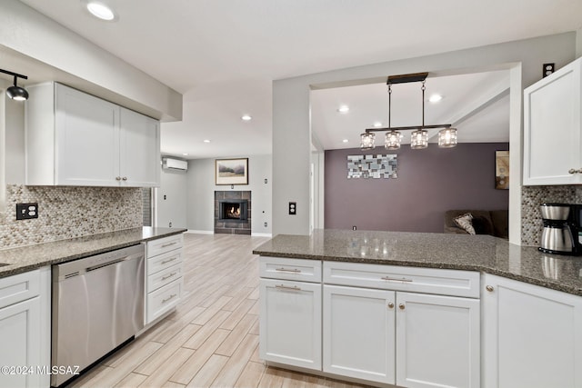 kitchen with white cabinets, dishwasher, decorative backsplash, and a fireplace