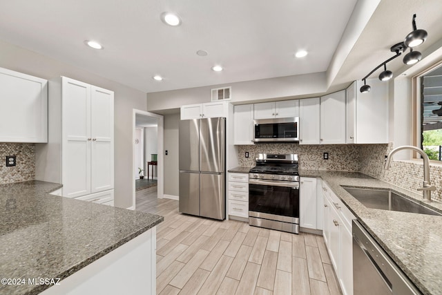 kitchen with dark stone counters, white cabinetry, sink, and stainless steel appliances