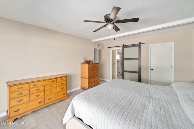 bedroom with a barn door, ceiling fan, and a textured ceiling