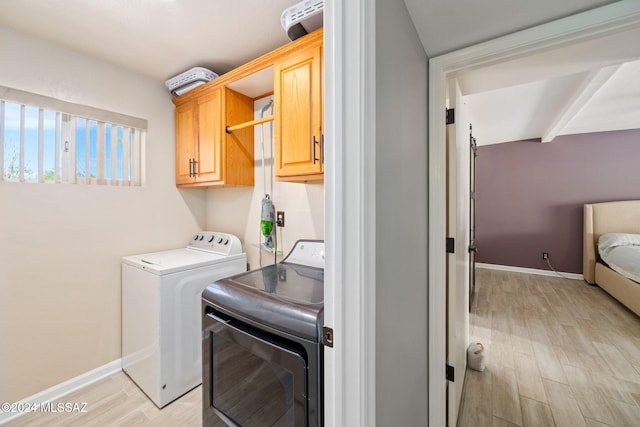 laundry room featuring washing machine and clothes dryer, light hardwood / wood-style flooring, and cabinets