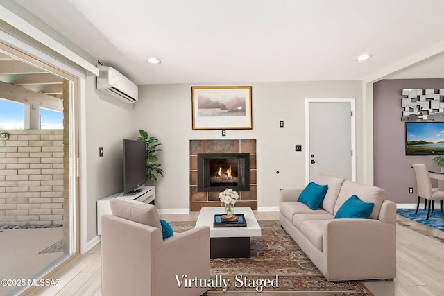 living room with a wall mounted air conditioner, wood-type flooring, and a tile fireplace