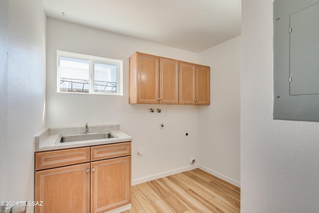 laundry room with electric panel, light wood-type flooring, hookup for a gas dryer, cabinets, and sink