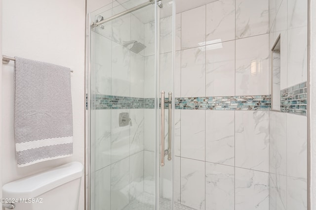 bathroom featuring a shower with door and toilet