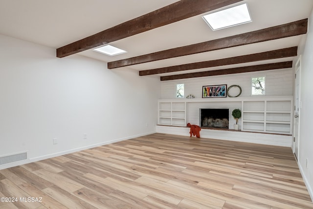 unfurnished living room with a brick fireplace, light wood-type flooring, and beamed ceiling