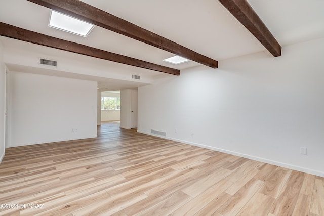 unfurnished room featuring beamed ceiling and light hardwood / wood-style flooring