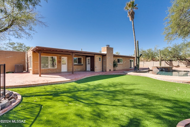 rear view of property featuring central air condition unit, a patio, a yard, and a fenced in pool