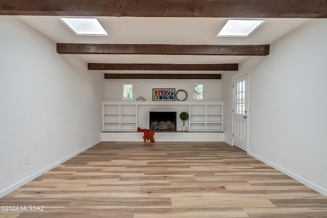 unfurnished living room featuring a brick fireplace, light wood-type flooring, and beamed ceiling