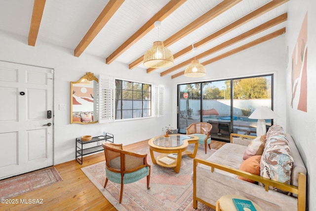 living area with a healthy amount of sunlight, vaulted ceiling with beams, and light wood finished floors