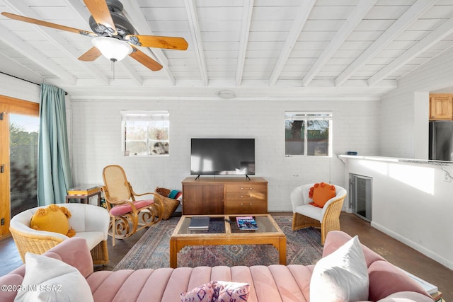 living room featuring brick wall, plenty of natural light, a fireplace, and beamed ceiling