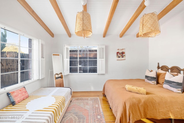 bedroom with beam ceiling and wood finished floors