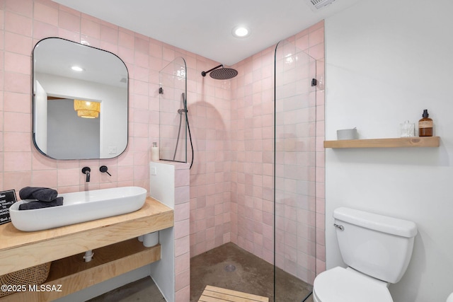 bathroom featuring a walk in shower, toilet, decorative backsplash, tile walls, and a sink