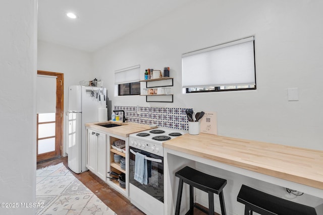 kitchen featuring white appliances, open shelves, a sink, a kitchen breakfast bar, and butcher block counters