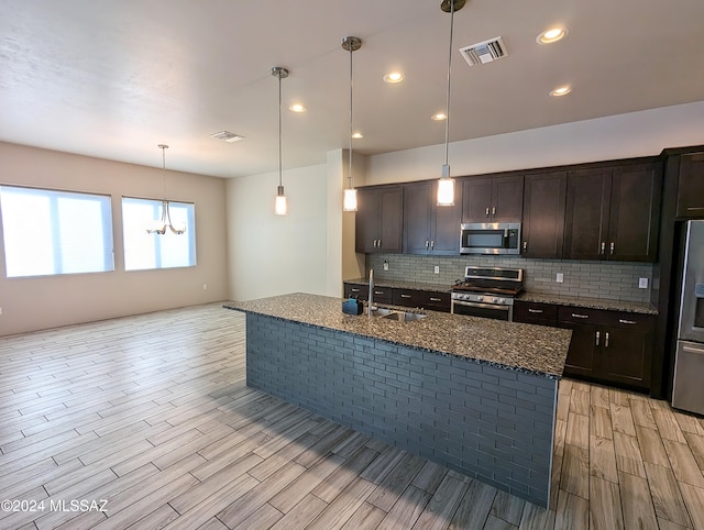 kitchen featuring appliances with stainless steel finishes, sink, light hardwood / wood-style floors, and hanging light fixtures