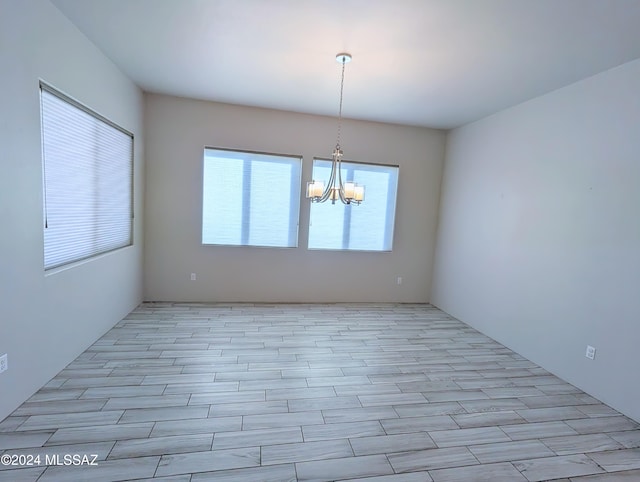 unfurnished room with a chandelier and light wood-type flooring