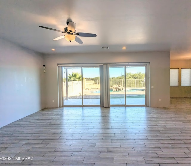 spare room featuring ceiling fan, a healthy amount of sunlight, and light hardwood / wood-style flooring