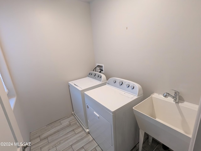 clothes washing area featuring sink, washer and dryer, and light hardwood / wood-style floors