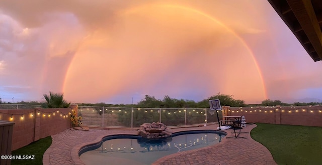 patio terrace at dusk featuring a fenced in pool