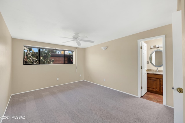 unfurnished bedroom featuring connected bathroom, sink, light colored carpet, and ceiling fan