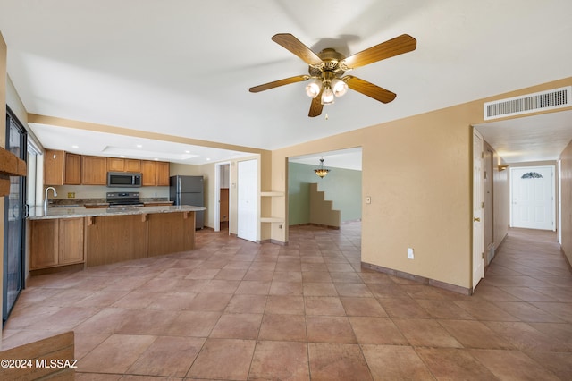 kitchen featuring sink, appliances with stainless steel finishes, kitchen peninsula, ceiling fan, and a breakfast bar area