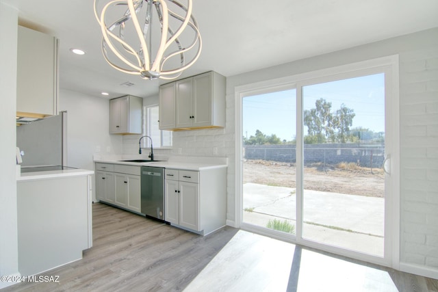 kitchen with dishwasher, an inviting chandelier, sink, and light hardwood / wood-style flooring