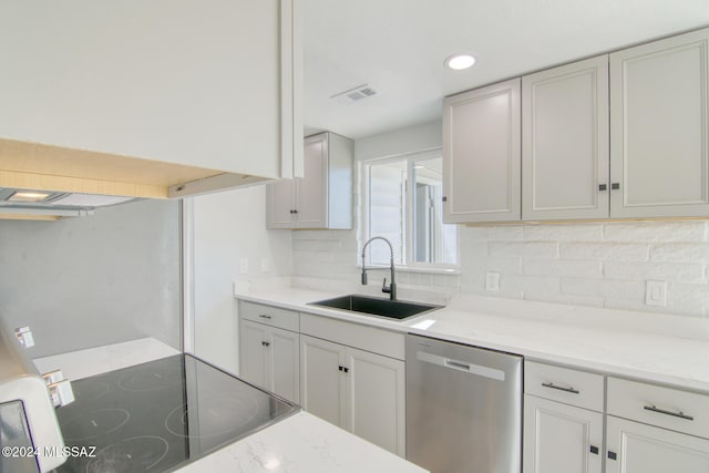 kitchen with sink, black range oven, light stone counters, stainless steel dishwasher, and backsplash