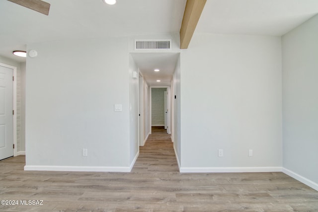 unfurnished room featuring light hardwood / wood-style floors and beam ceiling