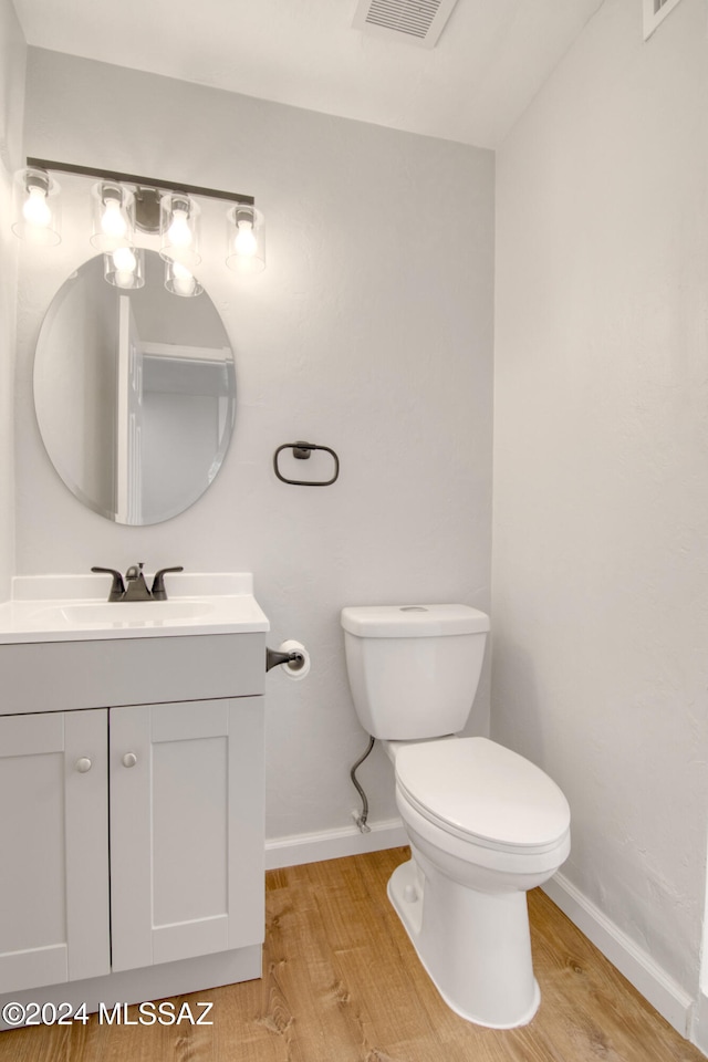 bathroom with toilet, vanity, and hardwood / wood-style flooring