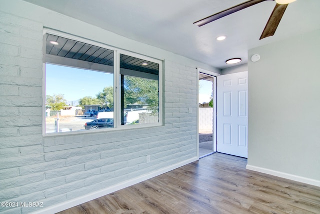 unfurnished room featuring hardwood / wood-style floors and brick wall