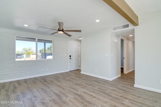 spare room featuring ceiling fan, light hardwood / wood-style floors, and brick wall