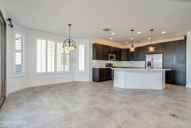 kitchen with pendant lighting, a barn door, a center island with sink, and stainless steel appliances