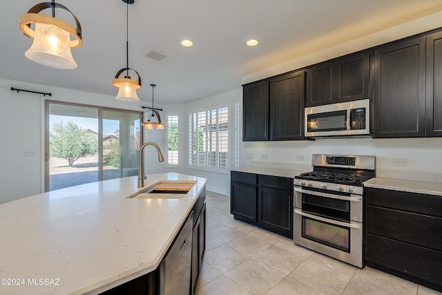 kitchen featuring stainless steel appliances, light tile patterned floors, sink, light stone countertops, and pendant lighting