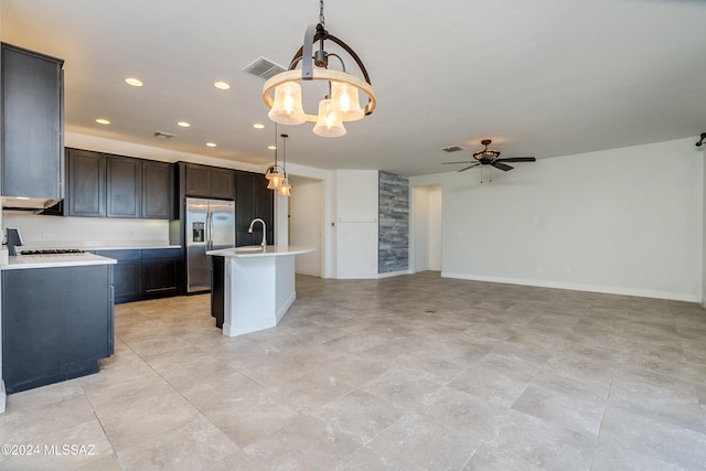 kitchen with a kitchen island with sink, stainless steel fridge with ice dispenser, range, pendant lighting, and ceiling fan with notable chandelier