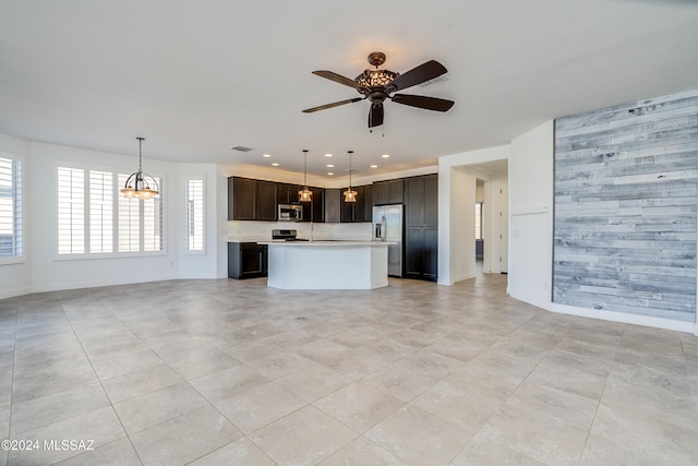 kitchen with appliances with stainless steel finishes, ceiling fan with notable chandelier, decorative light fixtures, dark brown cabinets, and a kitchen island