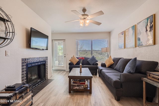 living room with ceiling fan, light hardwood / wood-style floors, and a fireplace