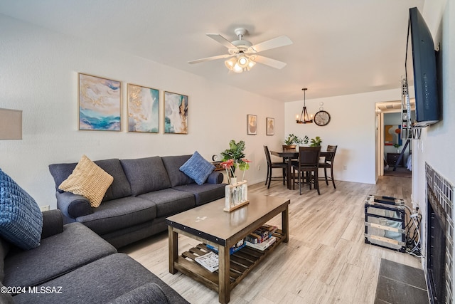 living room with ceiling fan with notable chandelier and light wood-type flooring