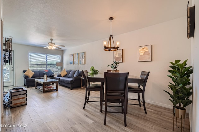 dining space featuring a textured ceiling, ceiling fan with notable chandelier, and hardwood / wood-style flooring