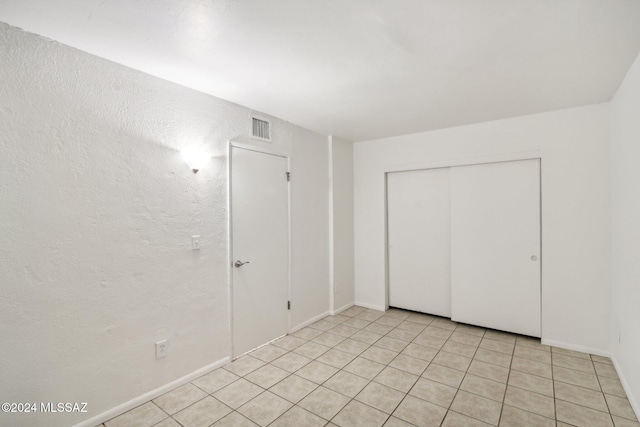 unfurnished bedroom with a closet and light tile patterned flooring