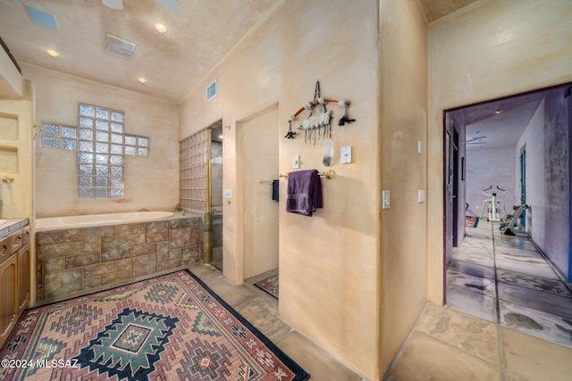 bathroom featuring tiled tub and ceiling fan