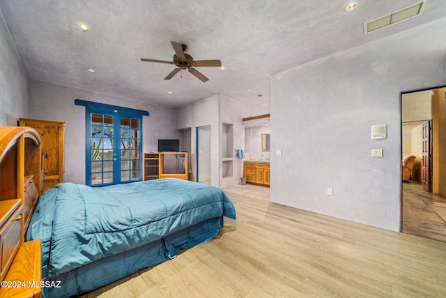 bedroom featuring light wood-type flooring, french doors, ceiling fan, and ensuite bathroom