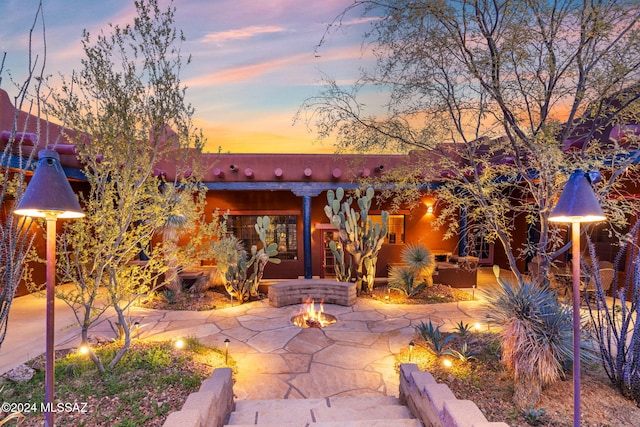 back house at dusk with a patio area and a fire pit