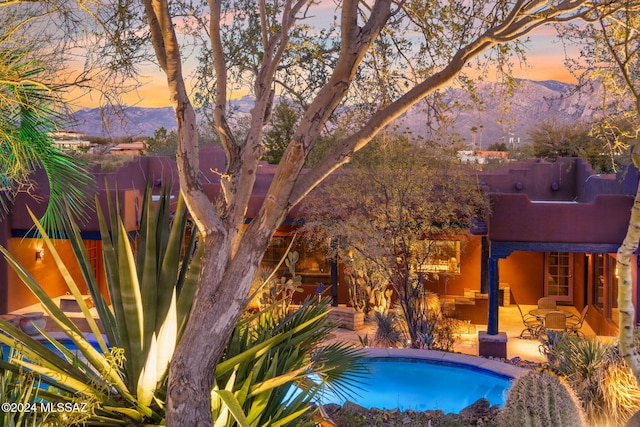 pool at dusk with a patio and a mountain view