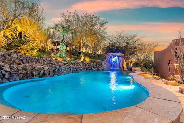 pool at dusk featuring pool water feature