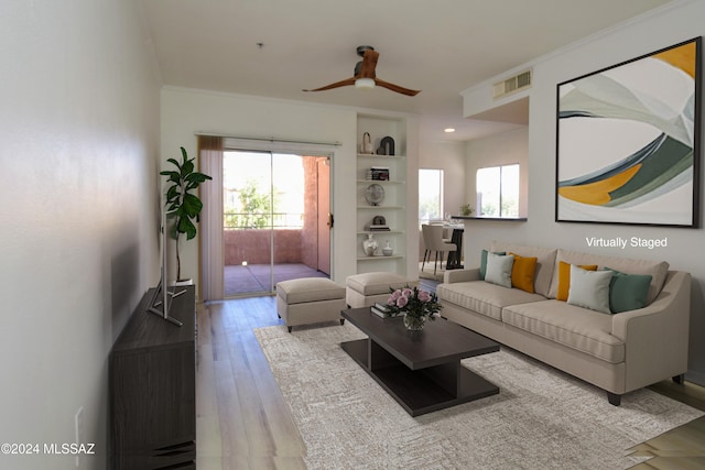 living room featuring ceiling fan, built in features, light wood-type flooring, and ornamental molding