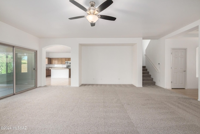 unfurnished living room featuring ceiling fan and light carpet