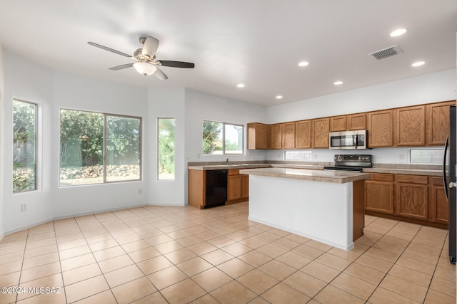 kitchen with appliances with stainless steel finishes, light tile patterned flooring, and a center island