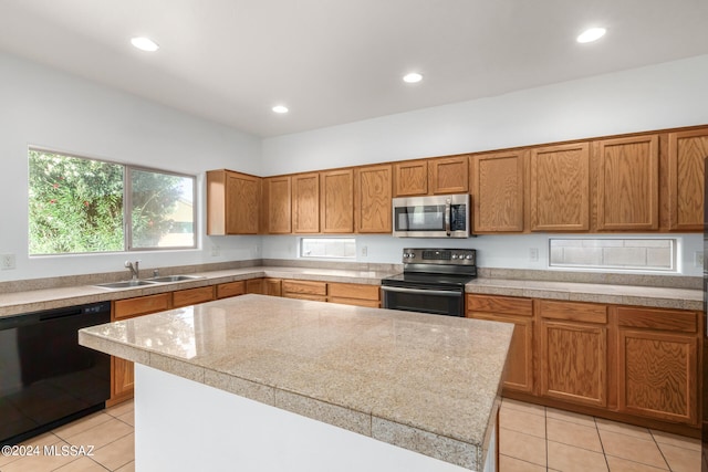 kitchen with stainless steel appliances, light tile patterned floors, a kitchen island, and sink