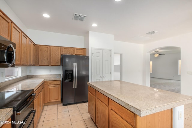 kitchen with black appliances, light tile patterned floors, a center island, and ceiling fan