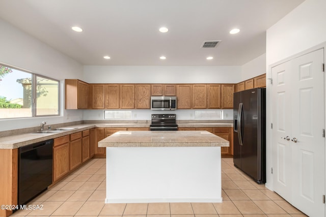 kitchen featuring black appliances, sink, light tile patterned floors, and a center island